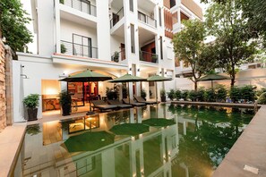 Um edifício moderno com piscina no terraço, espreguiçadeiras e guarda-sóis.
