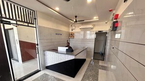 A reception area with a marble floor, a reception desk, a ceiling fan, and an air conditioning unit.