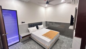 A bedroom with a bed, a nightstand, a wall-mounted TV, and a ceiling fan.