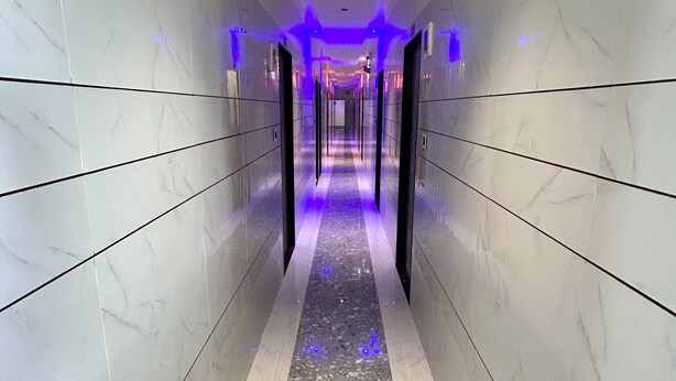 A hallway with marble walls and a terrazzo floor, leading to elevators.