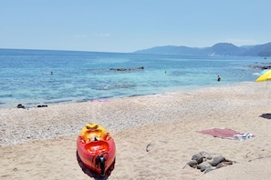 Uma praia com um caiaque, uma toalha e pedras.