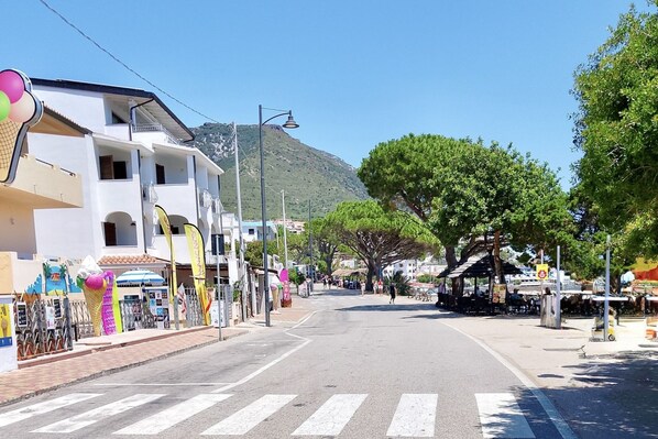A street with buildings, a crosswalk, and a kiosk. - Cala Gonone, 4-room apartment (4th floor) (Cala Gonone)