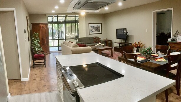 Una cocina moderna con una isla, un comedor con mesa y sillas, un sofá y una televisión en la sala.