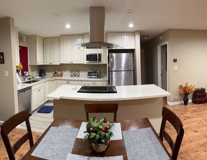 A kitchen with white cabinets, a stainless steel refrigerator, a microwave, and a toaster oven.