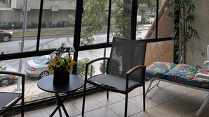 Un invernadero con vista a una calle, una mesa con un florero y una silla.