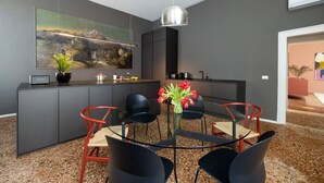 Een moderne keuken met een eethoek, een groot schilderij aan de wand en een vaas met bloemen op tafel.