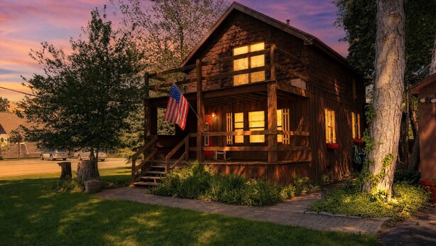A rustic log cabin with a porch, a staircase, and an American flag. - City Explorer Basecamp Buffalo 1 Bedroom Duplex with AC (Buffalo)