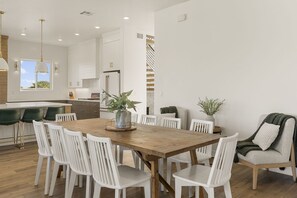 A modern kitchen with white cabinetry, a wooden dining table, and white chairs. - Grand Retreat At Coral Canyon 7 Bedroom Home (Washington)