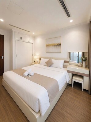 A hotel room with a large bed, bedside table, and a desk with a mirror. - Lyshing Apartment in Vinhomes Landmark (Ho Chi Minh City)