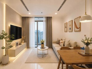 Een moderne woonkamer met een flatscreen televisie, bank, salontafel, eettafel en kunstwerken aan de muren.