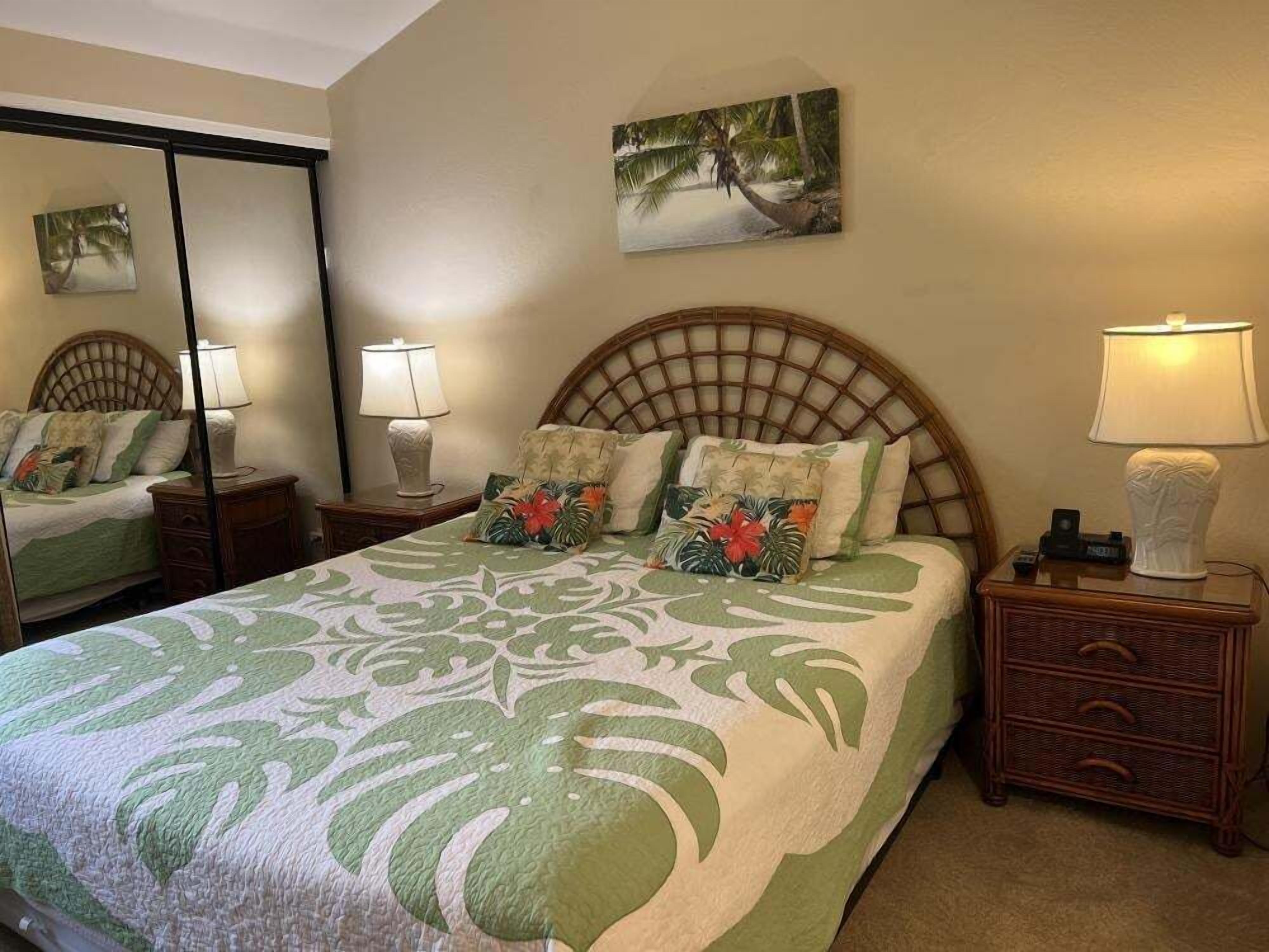 Une chambre à coucher avec un lit, une table de chevet, une lampe, un miroir et un tableau accroché au mur.