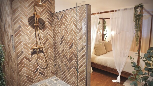 A modern bathroom with a herringbone tile wall, a glass shower enclosure, and a wooden floor. - Unique, romantic luxury suite in Bali with a jacuzzi, near the train station and close to the mountains (Grenoble)