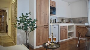 A modern kitchen with wooden cabinets, a built-in microwave, and a dining area with a wicker chair. - Unique, romantic luxury suite in Bali with a jacuzzi, near the train station and close to the mountains (Grenoble)