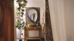 A bathroom with a wooden vanity, a round mirror, a potted plant, and a towel rack. - Unique, romantic luxury suite in Bali with a jacuzzi, near the train station and close to the mountains (Grenoble)