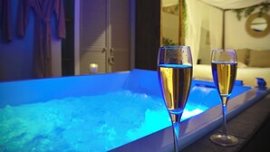 A room with a bathtub, two glasses of champagne, and a bed with a canopy. - Unique, romantic luxury suite in Bali with a jacuzzi, near the train station and close to the mountains (Grenoble)