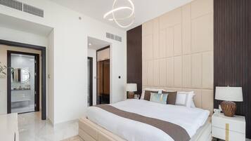 Un dormitorio moderno con una cama grande, lámparas de noche, un espejo y un armario.