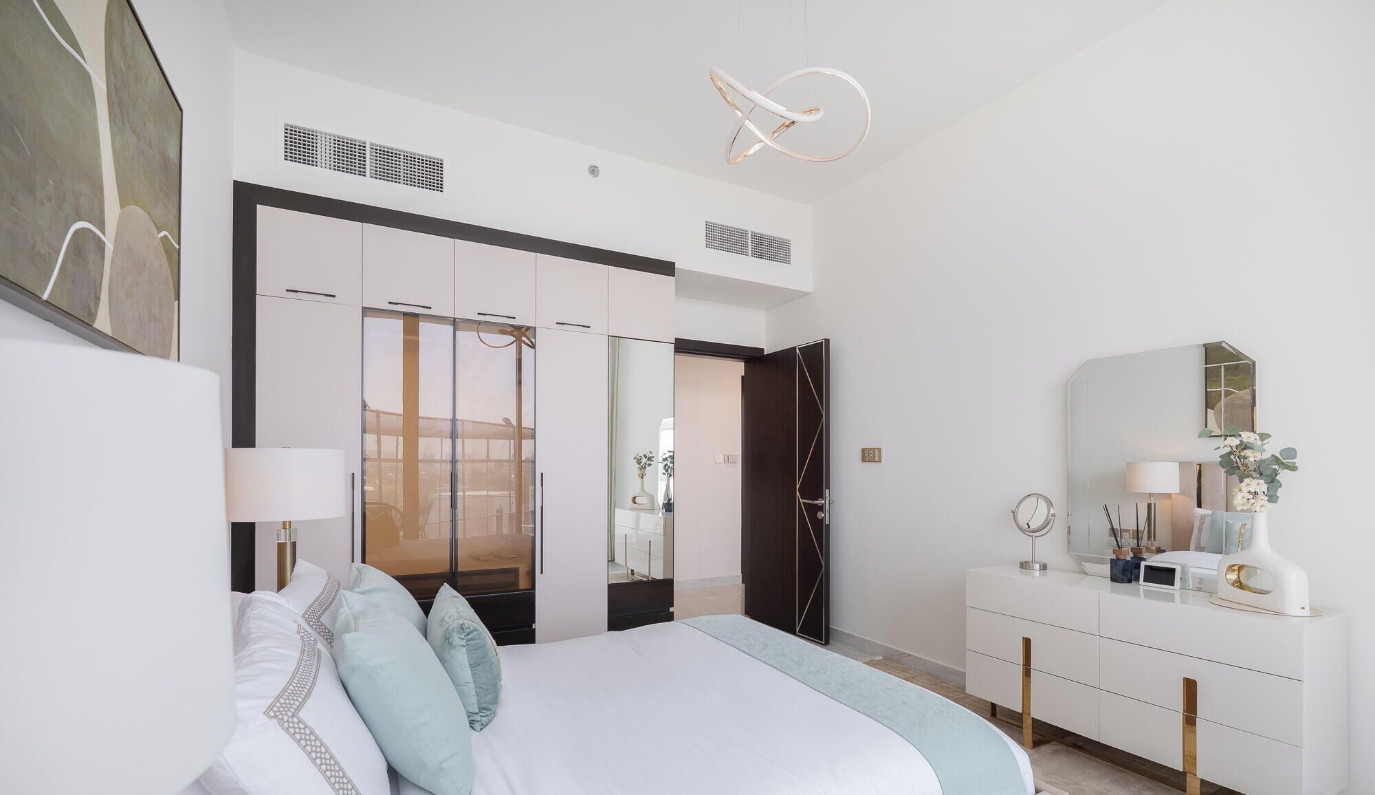 A modern bedroom with a bed, bedside tables, a dresser, a mirror, and a ceiling light fixture.