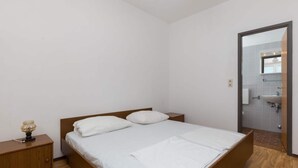 A bedroom with a single bed, a nightstand, a lamp, and a bathroom visible through an open door. - Rooms Villa Basica - Basic Double Room With Forest View (Mljet)