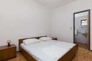 A bedroom with a single bed, a nightstand, a lamp, and a bathroom visible through an open door. - Rooms Villa Basica - Basic Double Room With Forest View (Mljet)
