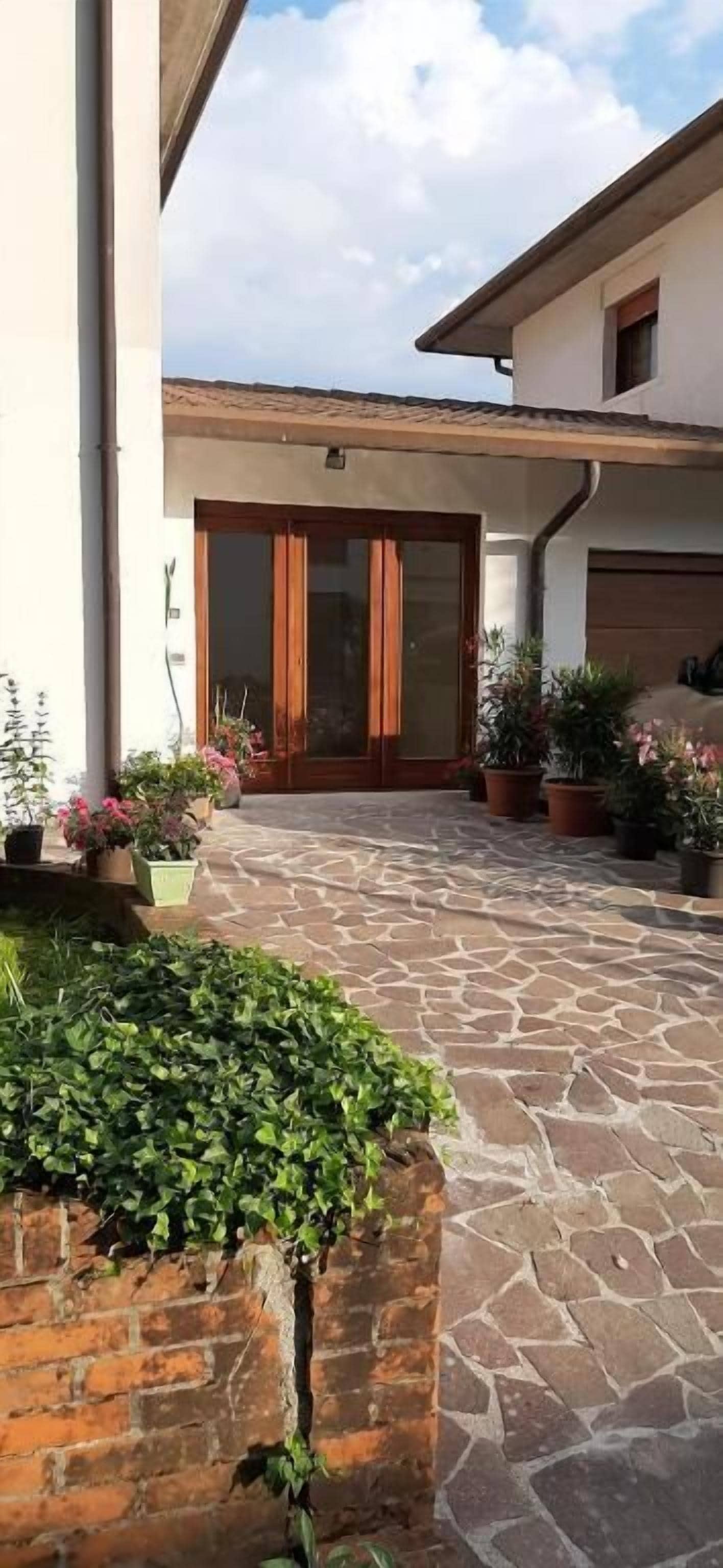 Un pati pavimentat amb plantes en testos i una porta de fusta.