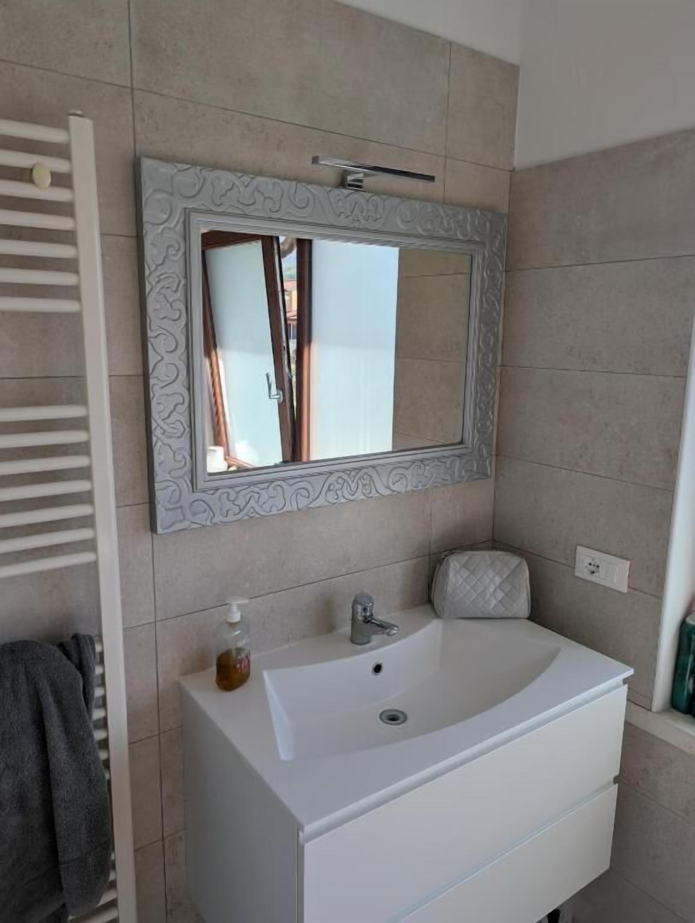A bathroom with a white sink, a mirror with a decorative frame, and a towel rack.