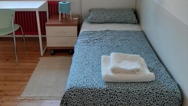 Una habitación pequeña con cama, escritorio y ventana.