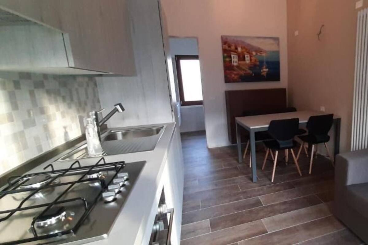 Una cucina moderna con piano cottura a gas, un'area pranzo con tavolo e sedie, e un divano nella zona living.