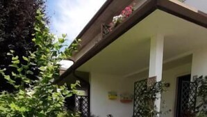Una casa con porche cubierto, pared de ladrillo cubierta de hiedra y jardín césped.