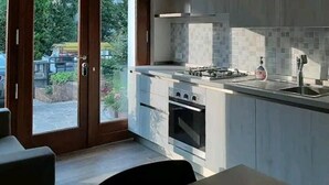 Cocina moderna con estufa a gas, horno y pileta, y puerta de vidrio corrediza que da a un patio.