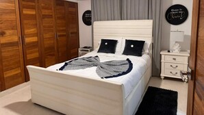A bedroom with a bed, wooden wardrobe, bedside table, and a ceiling fan. - Apartament 2 bedroms with their bathrooms  pool , gym , terrace and more (Santo Domingo)