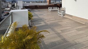 A rooftop terrace with a city view, potted plants, and modern outdoor furniture. - Apartament 2 bedroms with their bathrooms  pool , gym , terrace and more (Santo Domingo)