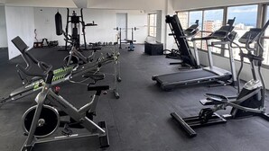 A gym with cardio machines, weightlifting equipment, and a large window offering a city view. - Apartament 2 bedroms with their bathrooms  pool , gym , terrace and more (Santo Domingo)