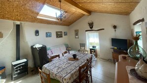 Una habitación acogedora con techo de madera, un sofá, una mesa de comedor con sillas, un televisor y una chimenea.