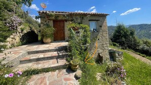 Una casa de piedra con una puerta de madera, un ventanal pequeño y una antena parabólica.