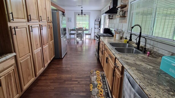 A kitchen with wooden cabinets, a granite countertop, a sink, and a window with blinds. - Wonderful 3-bedroom cottage in charming Diboll (Diboll)