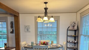 A dining area with a round table, four chairs, a chandelier, and a window with blinds. - Wonderful 3-bedroom cottage in charming Diboll (Diboll)