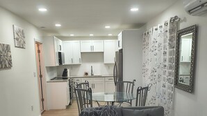 A modern living room with a grey sofa, a glass coffee table, and a dining area with a glass table and chairs. - Cozy 1-BR/BA cottage in beautiful Stonecrest near I-20 & I-285, Arabia Mountain (Stonecrest)