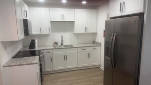 A kitchen with white cabinets, a stainless steel refrigerator, and a granite countertop. - Cozy 1-BR/BA cottage in beautiful Stonecrest near I-20 & I-285, Arabia Mountain (Stonecrest)