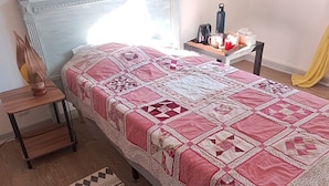 Una camera da letto con un letto, un comodino, una lampada, un quadro incorniciato, un tappeto e uno specchio fissato alla parete.