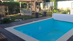 Una piscina rettangolare con bordo bianco, circondata da un pontile in legno.
