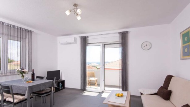 A modern apartment with a dining area, a sofa, a small wooden table, and a balcony with a view. - Peaceful Apartments Harfa- One Bedroom Apartment With Balcony and Partial Sea View 2 (Orebic)