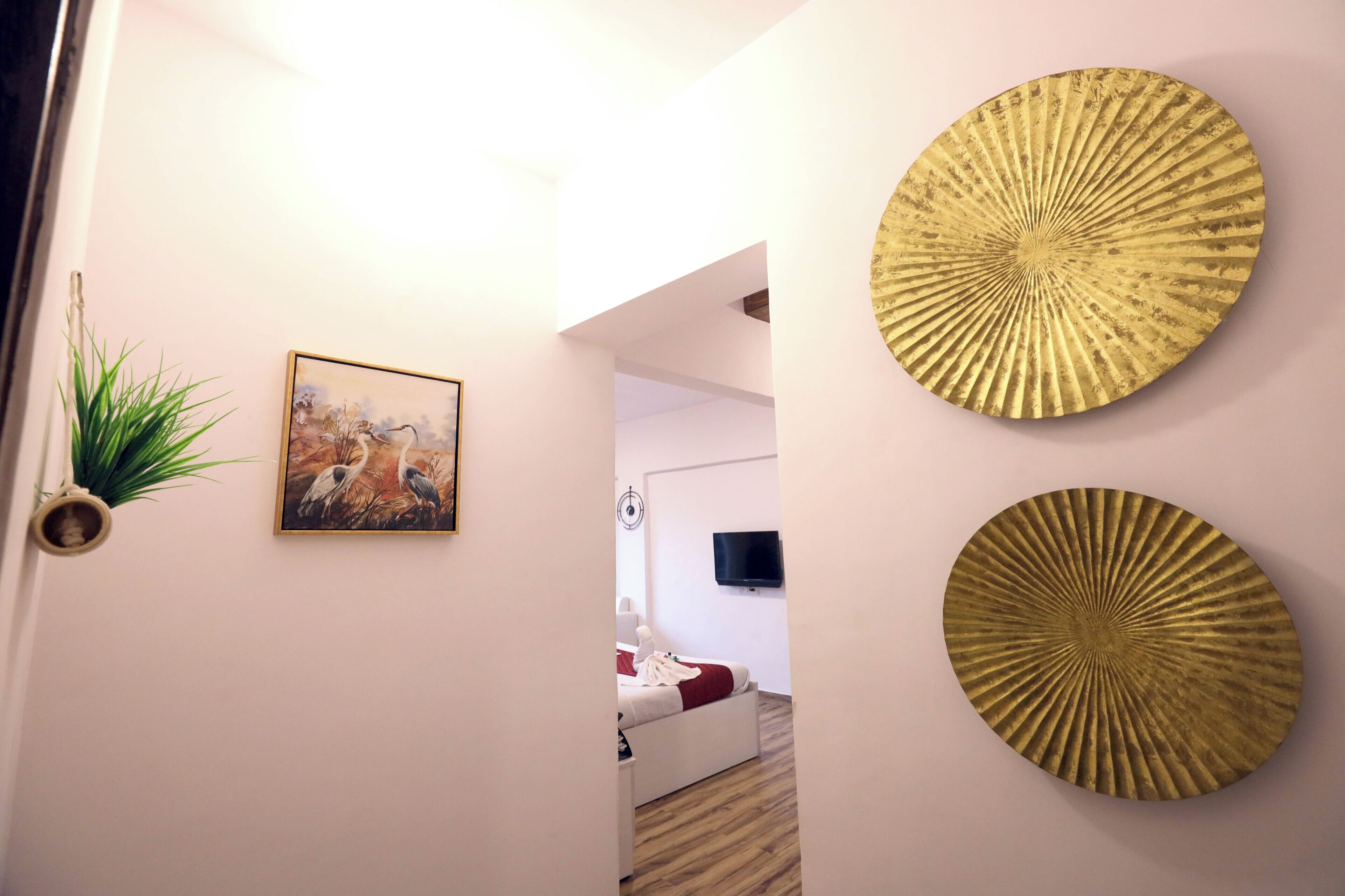 Un couloir comprenant un lit, un téléviseur fixé au mur et deux assiettes décoratives en or.