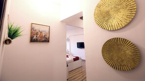 Un pasillo con una cama, un televisor de pared y dos placas decorativas doradas.