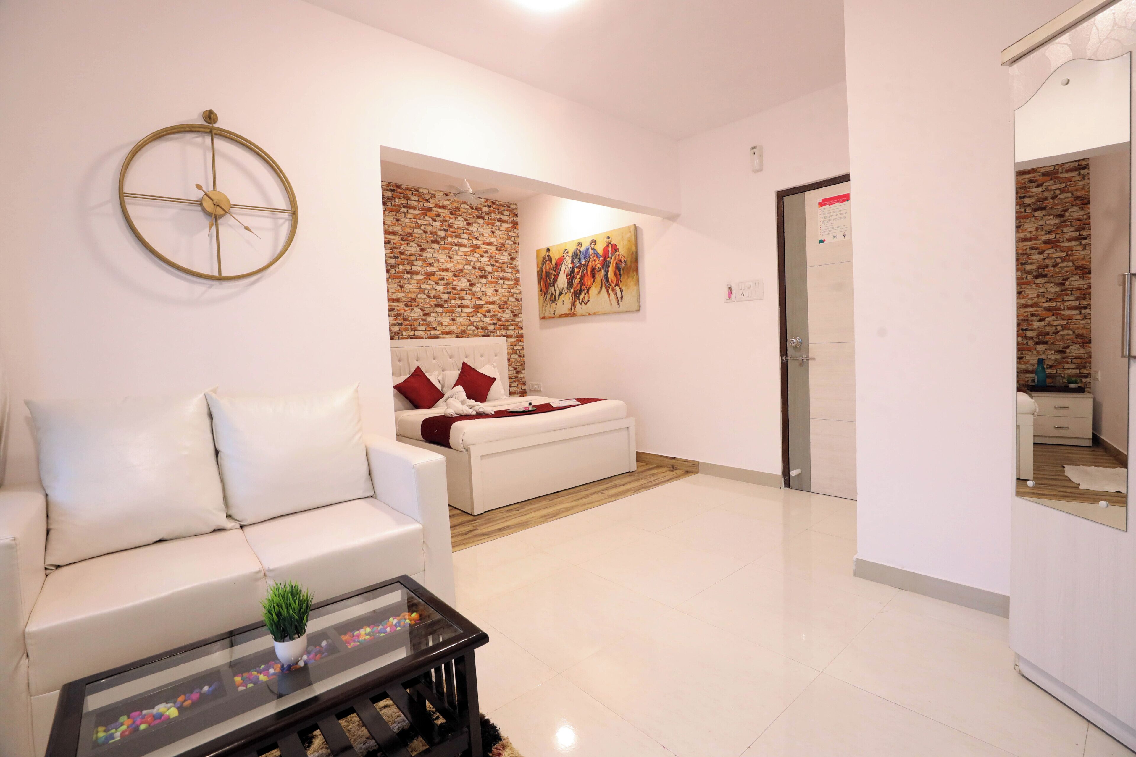 Una sala de estar moderna con un sofá blanco, una mesa de centro de vidrio, una pared de ladrillo decorativa y un cuadro.