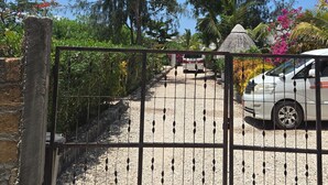 Une entrée fermée par un portail, avec une allée gravillonnée menant à un bâtiment.