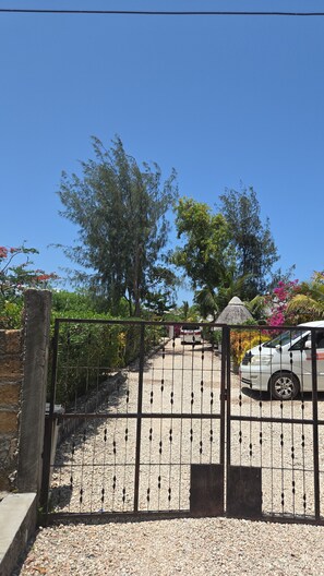 A gated entrance with a gravel driveway leading to a building.