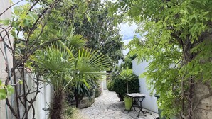 A stone-paved courtyard with potted plants, a metal table, and a wall. - Charming house near Chaucre Beach (Saint-Georges-d'Oléron)