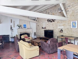Uma sala de estar com lareira, sofás de couro, televisão e paredes de pedra.