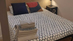 Un lit avec une couvre-lit à motifs géométriques, une tête de lit à motifs chevrons et une petite table de chevet avec une lampe.
