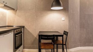 Une cuisine moderne avec une table à manger, des chaises, un luminaire suspendu et un four encastré.